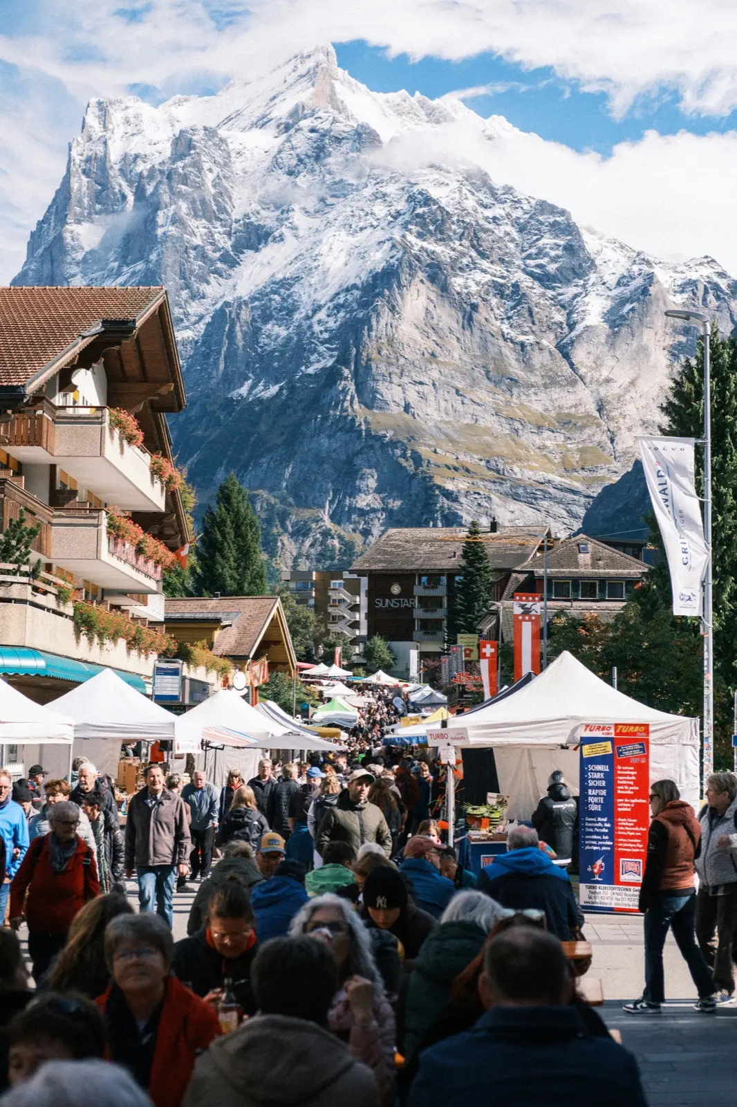 Dorfmarkt mit Ständen und Besuchern vor Bergkulisse im Berner Oberland: Website für Anlässe und Feste